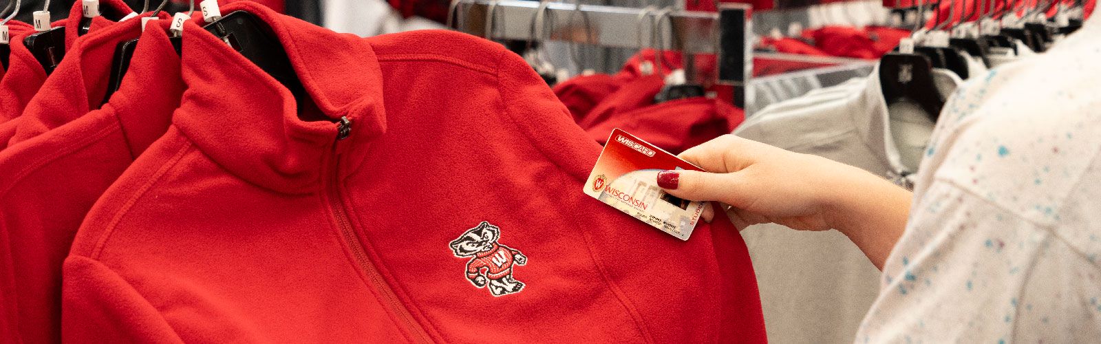A shopper browsing UW apparel with a Wiscard in their hand.